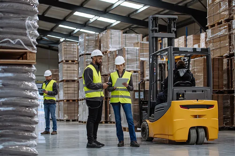 Employees using a tablet to manage stock levels and shipments, showcasing the user-friendly features of WMS software.